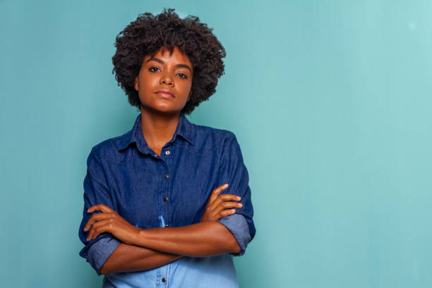 schwarze junge frau mit schwarzen power-haaren trägt ein blaues jeanshemd auf blauem hintergrund - fashion model audio stock-fotos und bilder