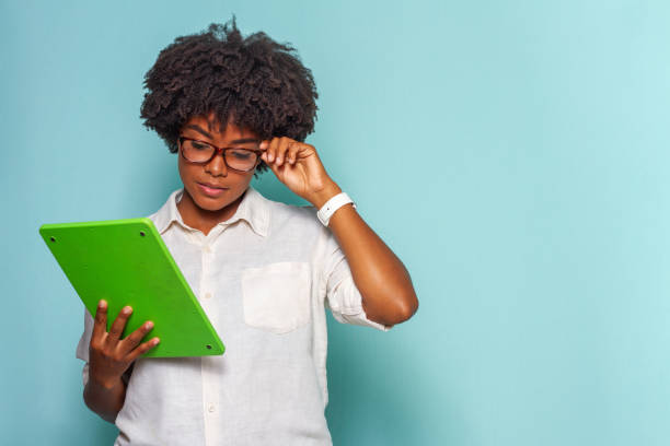 Black young woman curly hair using a tablet Black young woman with glasses and black power hair wearing a light shirt with tablet and pen in hands looking at the viewer drawing board stock pictures, royalty-free photos & images