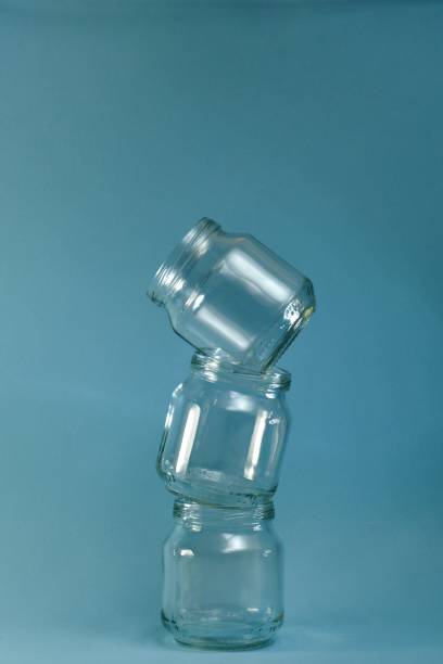 istock Vertical row of glass curved pyramid built jars on a vertical blue background. 1226680320