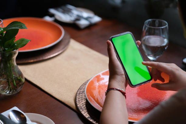 istock over shoulder of people tapping green screen smartphone in restaurant. 1226688361