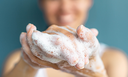 Closeup shot of person's hands being washed with soap suds