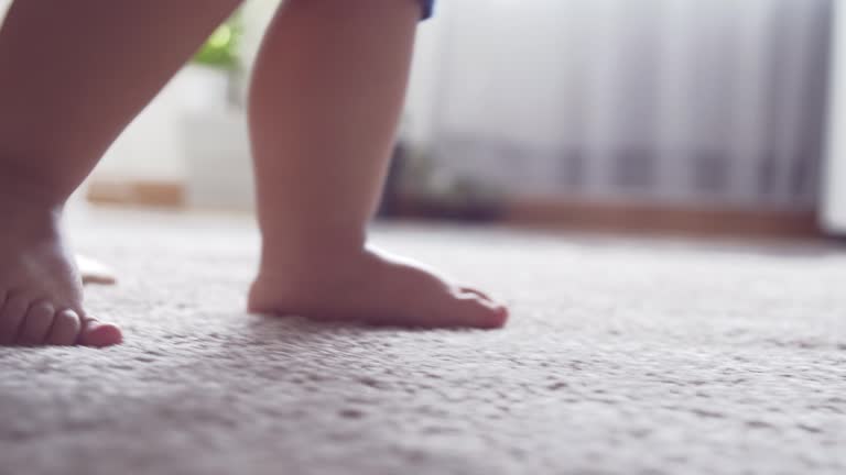 Mother support little boy walking at home