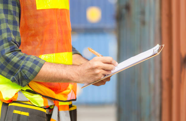 istock Close up of Worker man holding clipboard checklist and checking containers box from cargo 1226691449
