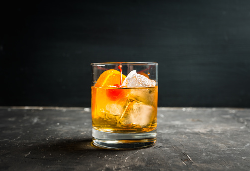 Old fashioned beverage with orange slices on rustic background. Selective focus. Shallow depth of field.