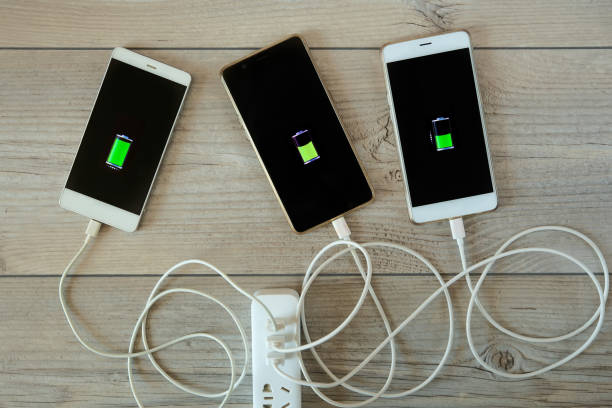 Smartphones are charged from the charger and lie side by side stock photo