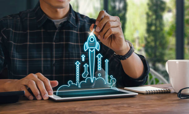 Business start up, start, new project or new idea concept. Wooden blocks with launching rocket graphic arranged in pyramid shape and a man is holding the top one.