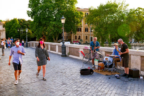 Some street musicians play along Ponte Sisto in the Trastevere district in the historic center of Rome Rome, Italy, May 22 -- Some street artists play on the ancient Ponte Sisto near Trastevere, while people walk protected by a medical mask during the slow reopening towards a normal life after two months lockdown due to Covid-19. opening bridge stock pictures, royalty-free photos & images