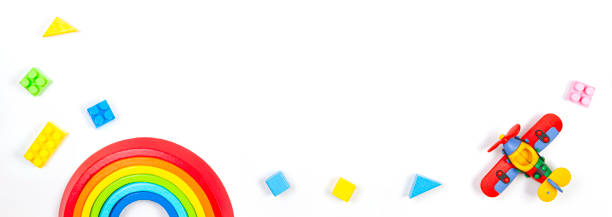 istock Baby kids toys banner background. Constructor airplane, stacking toy rainbow and colorful blocks on white background. Top view, flat lay 1226703295