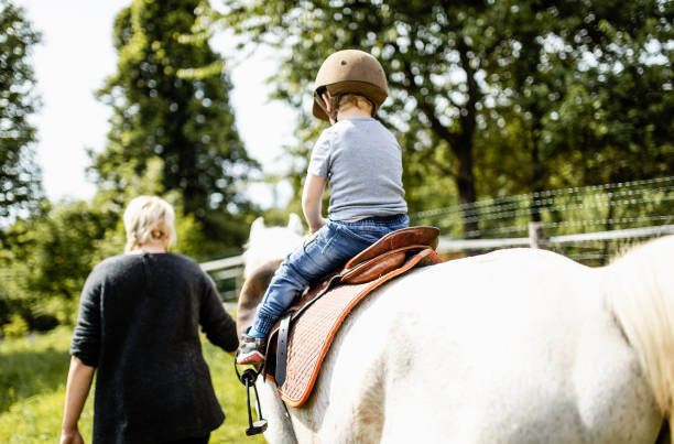 istock Young woman teaching a boy how to ride a horse 1226703373