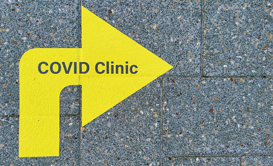 COVID clinic yellow direction arrow on pavement