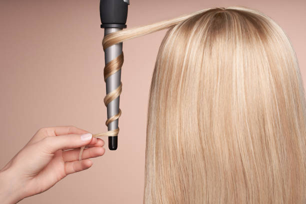 The hairdresser curls long hair with a Curling iron The hairdresser curls long hair with a Curling iron. Beautiful woman with long straight hair. Smooth hairstyle curling tongs photos stock pictures, royalty-free photos & images