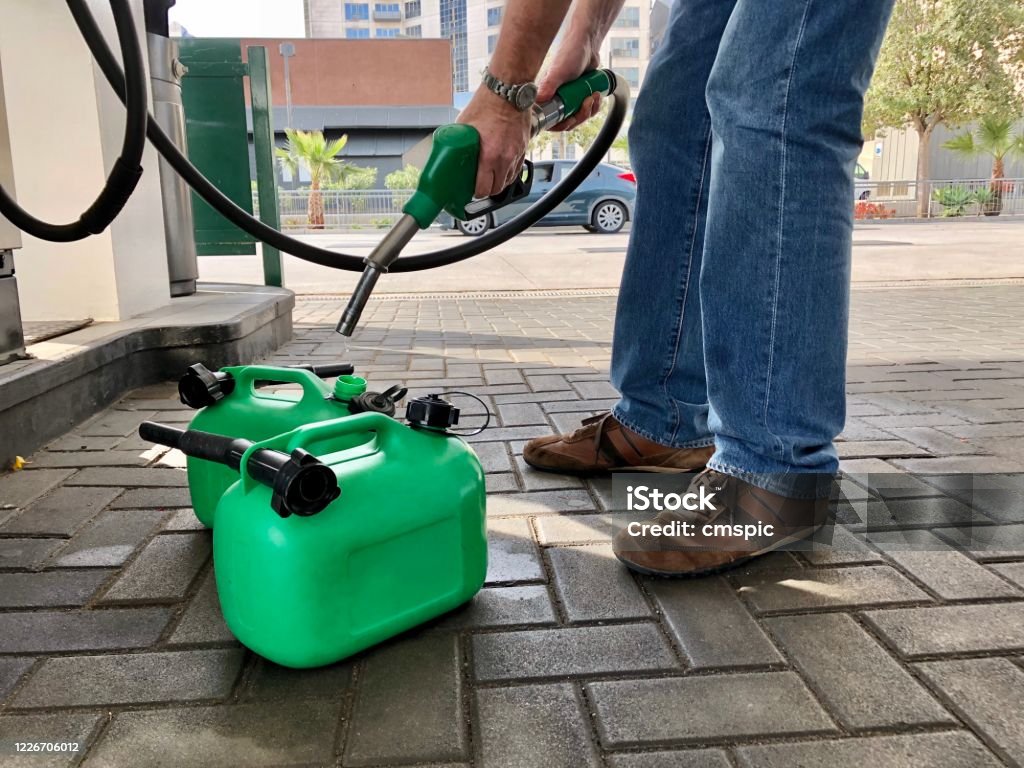 Filling fuel cans Man filling plastic fuel cans at a petrol station Gas Can Stock Photo