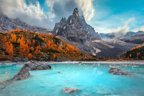 Picturesque hiking, photography and recreation place. Stunning lake Sorapis with colorful larches and high mountains. Beautiful autumn landscape in the Dolomites, Italy, Europe