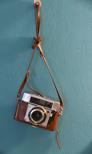 Vintage film camera with leather case hanging at wall, Decoration