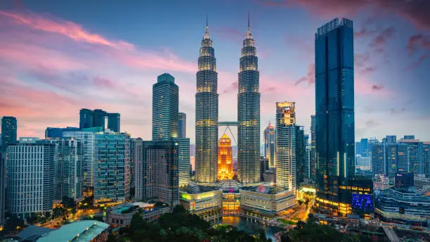 Panorama of the iconic illuminated Petronas Towers in downtown Kuala Lumpur during a colorful Sunset Twilight - Night. Kuala Lumpur, Malaysia, Southeast Asia.