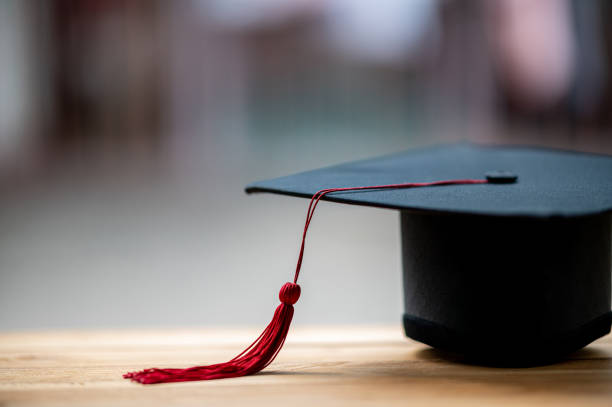 istock closeup, black graduated hat and red tassels placed on wood and copyspace 1226717561