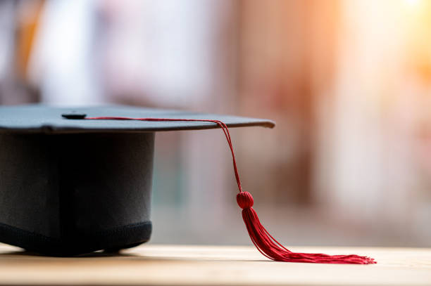 istock closeup, black graduated hat and red tassels placed on wood and copyspace 1226717564