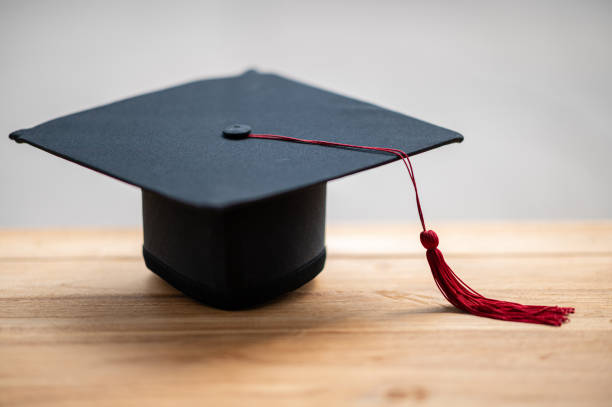 istock closeup, black graduated hat and red tassels placed on wood and copyspace 1226717571