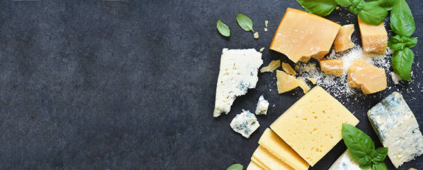 istock Cheese set: brie, blue cheese, parmesan and basil on a black concrete background. View from above. 1226723438