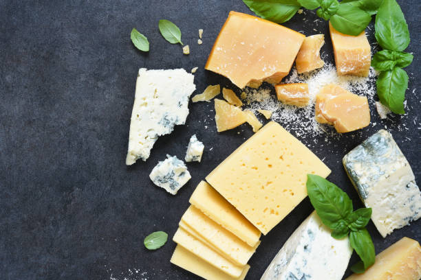 istock Cheese set: brie, blue cheese, parmesan and basil on a black concrete background. View from above. 1226723455