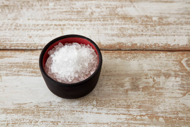 Natural halite in stone bowl on wooden table. stock photo