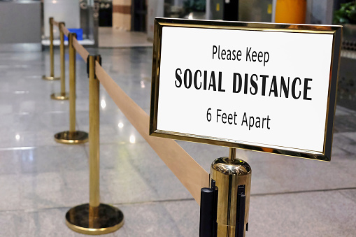 Close up of shot of social distancing signage board attached on airport security barrier