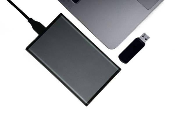 istock Flat lay of a mobile HDD, usb flash drive and a silver laptop. Directly above, isolated on white. 1226729517