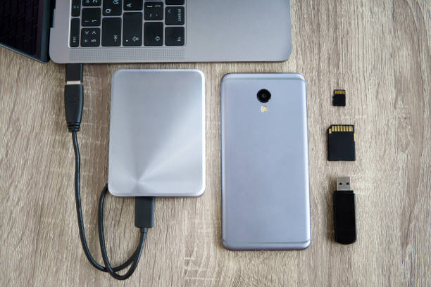 istock Laptop and mobile phone data transfer peripherals - portable HDD, usb flash drive and SD cards - lying on a wooden table. 1226729673