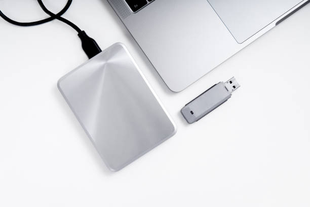 Flat lay of a mobile external hard disk drive, flash stick and a laptop. Portable hdd connected to a laptop and a usb flash drive on a grey background, flat lay. Data storage concept. external hard disk drive stock pictures, royalty-free photos & images