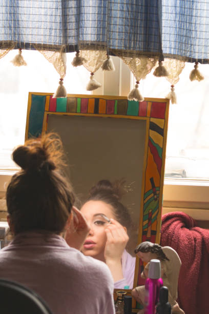 istock Young woman looking at herself in the mirror and applying make-up. 1226730234