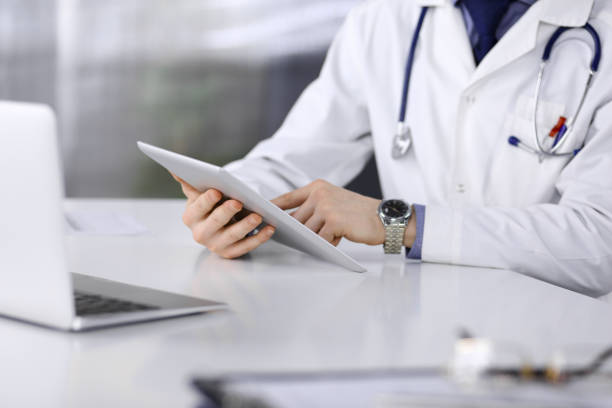 istock Unknown male doctor sitting and working with tablet computer in clinic at his working place, close-up. Young physician at work. Perfect medical service, medicine concept 1226731673