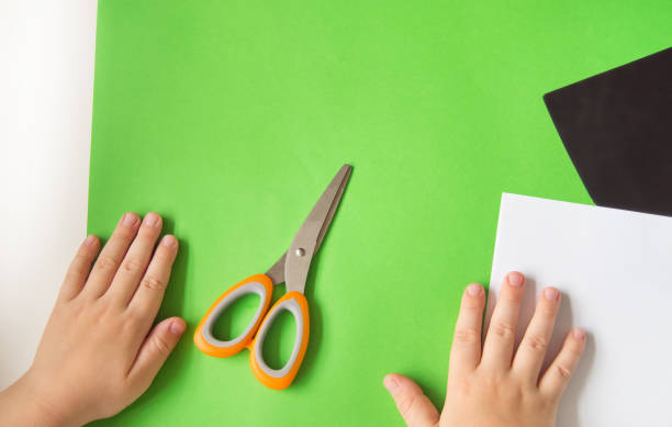 istock The concept of DIY and children's creativity. Step-by-step instructions: how to make a Panda application from paper. Step 1 Prepare colored paper and scissors, the child's hands on the table 1226735549