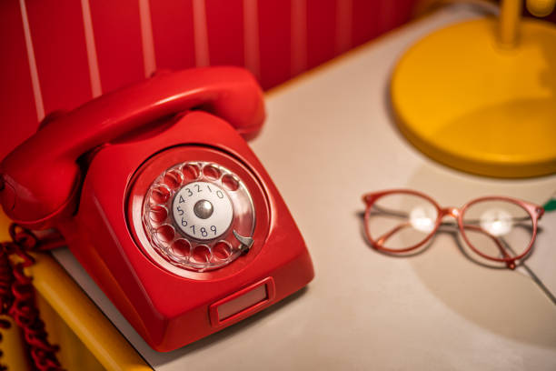 Old red telephone with rotary dial on the table with old glasses Image of Old red telephone with rotary dial on the table with old glasses bakelite stock pictures, royalty-free photos & images