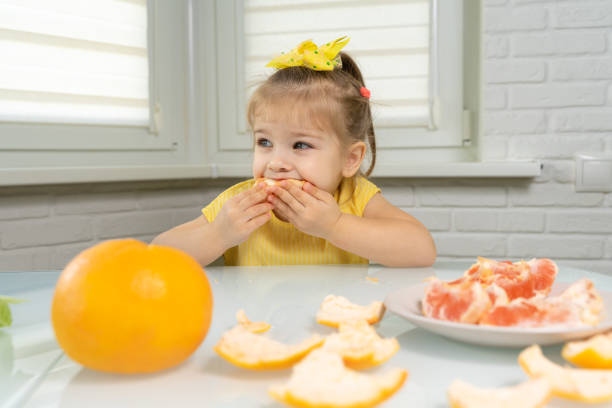 istock little girl eating grapefruit 1226744833