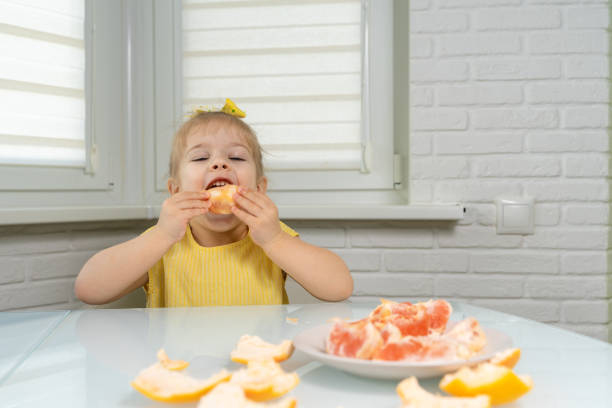 istock little girl eating grapefruit 1226744836