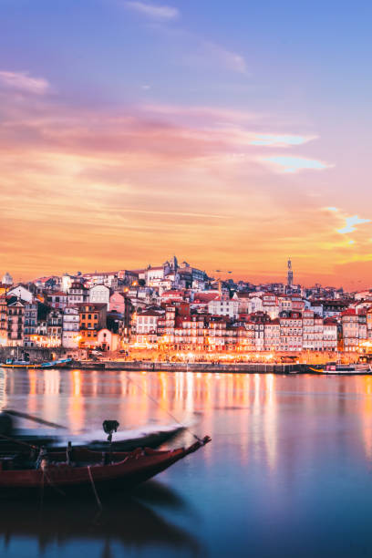 Vertical landscape view with a Rabelo boat and Douro river in the ribeira in Oporto City at sunset Located along the Douro River estuary in northern Portugal, Oporto is one of the oldest European centres, and its core was proclaimed a World Heritage Site by UNESCO in 1996, as "Historic Centre of Oporto, Luiz I Bridge and Monastery of Serra do Pilar". The historic area is also a National Monument of Portugal. rabelo boat stock pictures, royalty-free photos & images