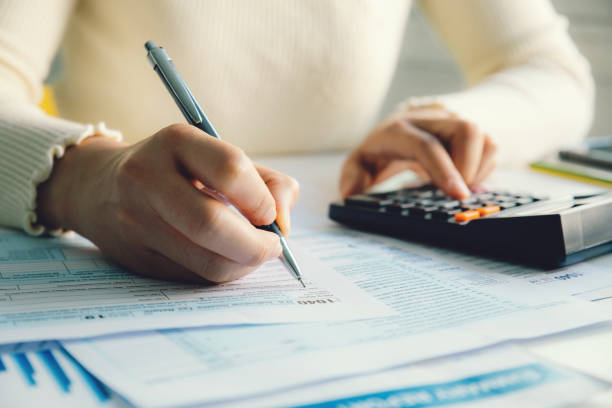 closeup woman filling form of individual income tax return, - tax tax form financial advisor calculator imagens e fotografias de stock