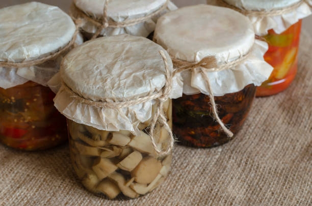 Homemade canned food. Canned food in glass jars. Various canned food on burlap. Preservation and storage of crops. Close-up.