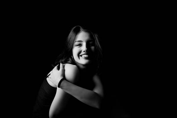 Black and white young woman looking at camera isolated on black background. stock photo