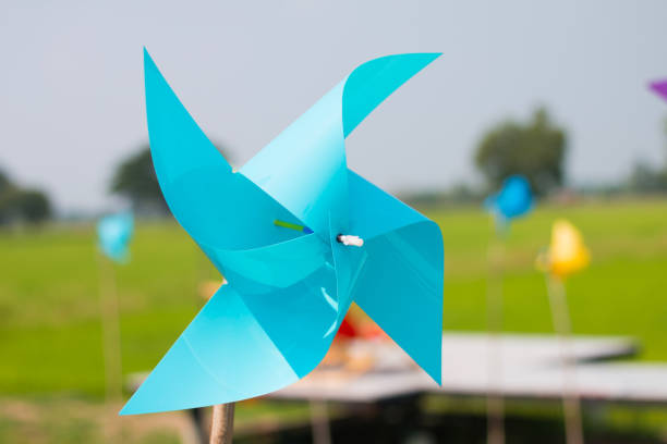 istock Blue toy windmill with four points With a background image of lush green fields On a clear day and clear sky 1226754485