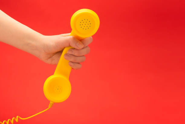 istock Yellow handset on a red background in woman hand. 1226754957