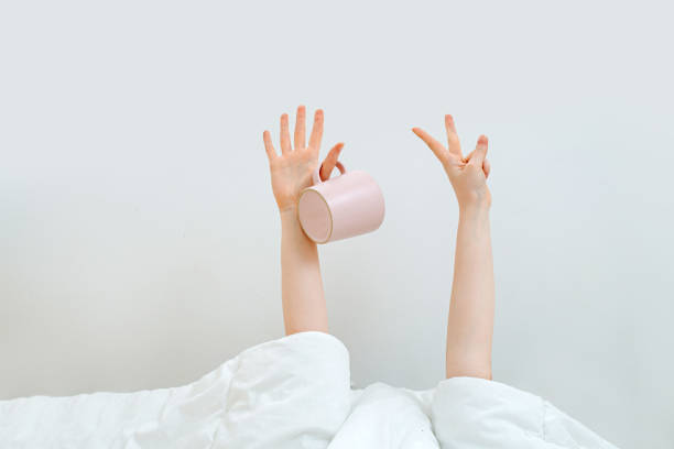 istock Girl's hands with a cup, she is still under the covers. Demanding coffee 1226757442