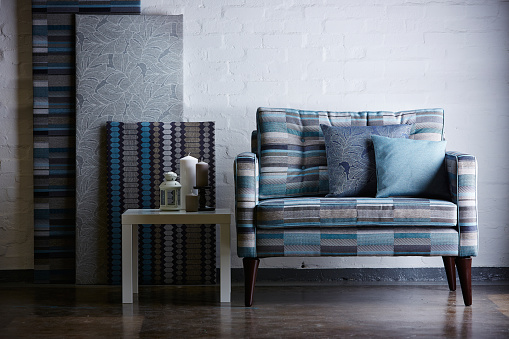 Shot of a modern sofa and material panels against white brick wall