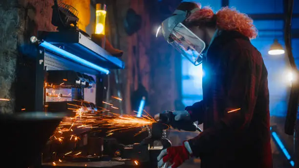 Talented Female Fabricator Uses an Angle Grinder to Polish a Circular Metal Object. The Ring is Gripped in a Bench Vise. Beautiful Tomboy Engineer Creating Working on Steel Parts.