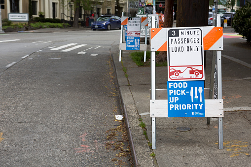 The city of Seattle is one of the epicenters of the coronavirus COVID-19 outbreak.  The government shutdown of non-essential businesses has closed many public places including shops, restaurants, bank lobbies and more.  Seattle has created restaurant food pickup zones and placed signs throughout the city to support essential services.