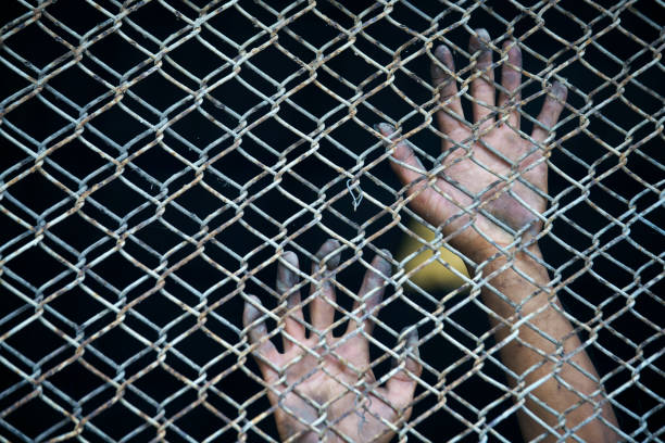 hands of prisoner in jail background.