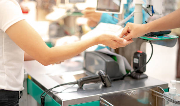 Female hand with coin money pay for goods concept. Hand giving cash and hand receiving cash, paying checkout at cashier access in supermarket. stock photo