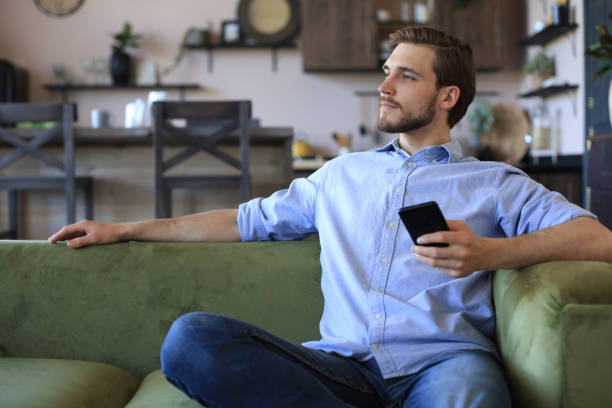 istock Attractive young man relaxing on a couch at home and using mobile phone for cheking social nets. 1226763602