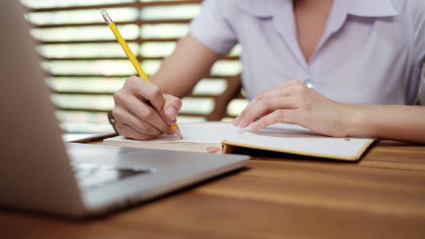 istock Young girl writing note with pen inspired ideas list on notepad while working on laptop computer 1226764194