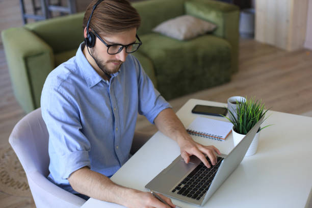istock Concentrated young freelancer businessman using laptop for video conferance, working remotely online at home. 1226764387